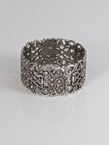 A silver filigree band ring with a detailed, intricate pattern.